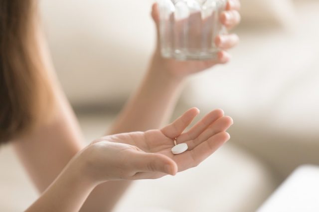 Woman takes medicines with glass of water