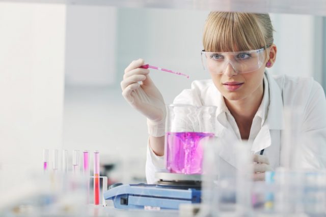 doctor student female researcher holding up a test tube in chemistry bright labaratory