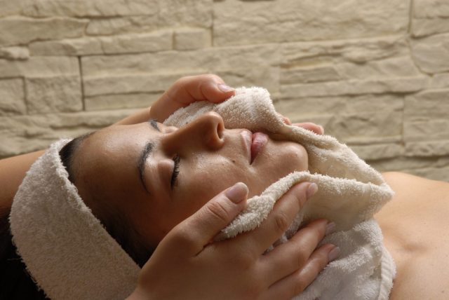 Beautiful young woman getting a warm towel compress