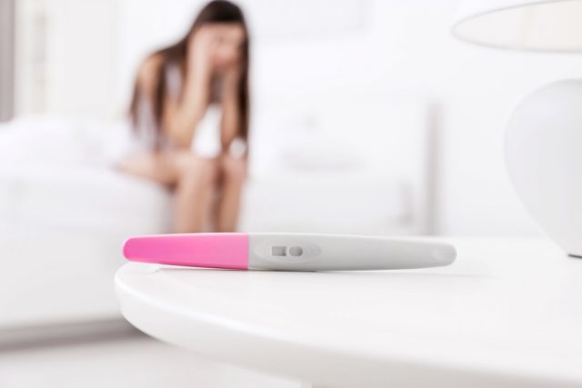 Pregnancy test and blurred woman suffering from headache - Bloody Discharge