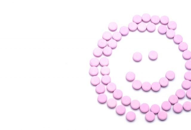 Bloody Discharge - Smile face of pink pills on white background