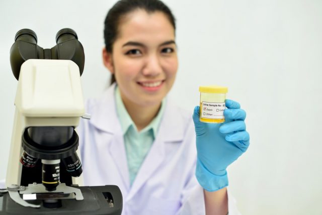 Medical technologist show urine sample for analysis