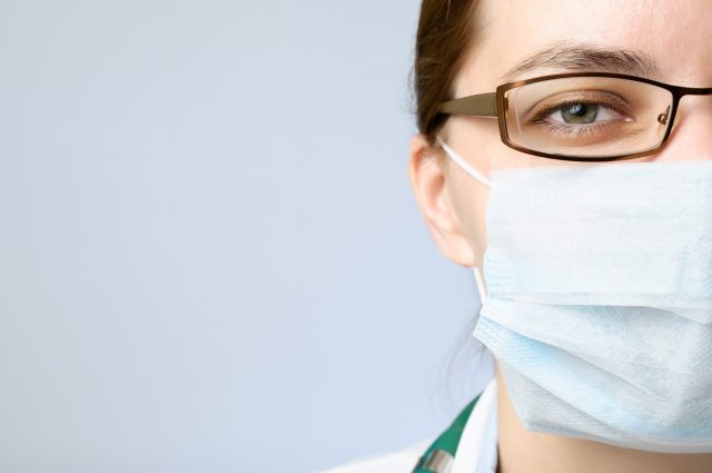Female doctor in face mask looking at camera