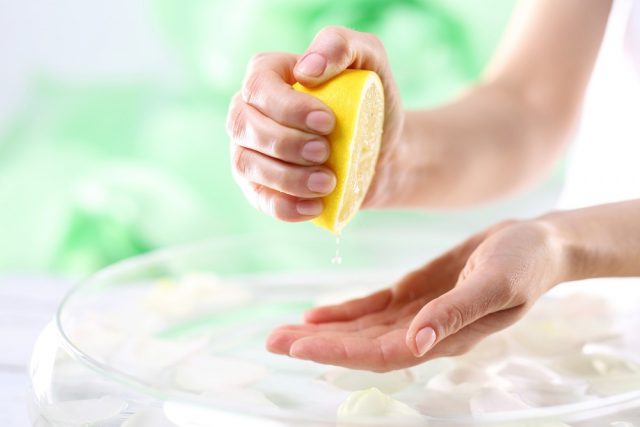 Lemon juice, natural cosmetics. The woman squeezed the palm lemon juice