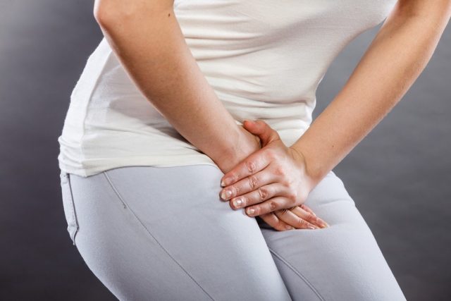 Young sick woman with hands holding pressing her crotch lower abdomen