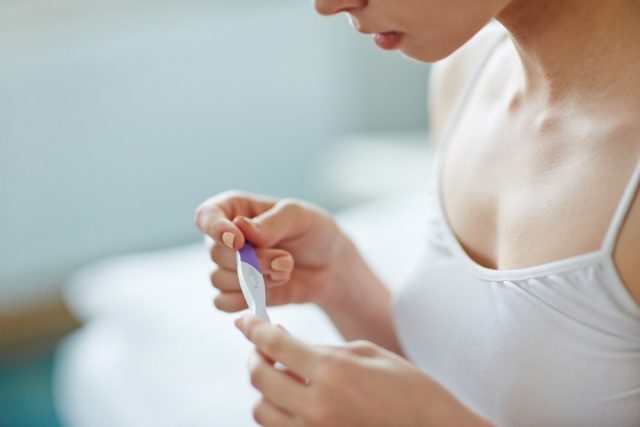 Young woman with pregnancy test in hands