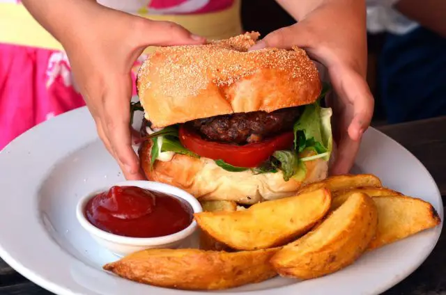 Hands of a little girl ready to eat a big hamburger