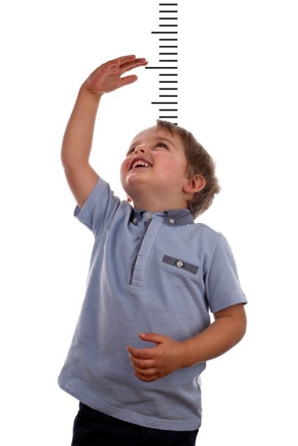 Young boy measuring his growth in height