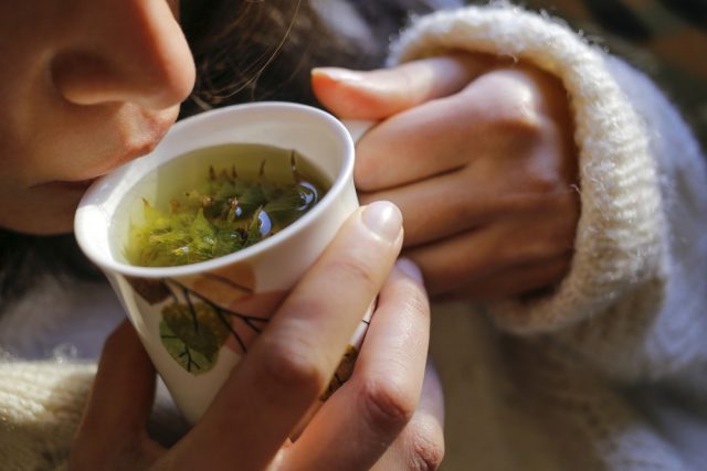 A young woman on the couch and with sage tea on the hand