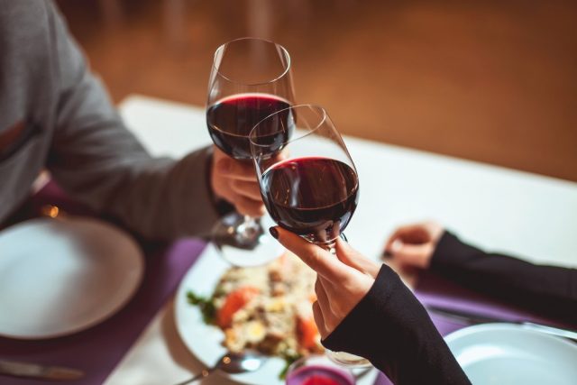 Beautiful young couple with glasses of red wine in luxury restaurant