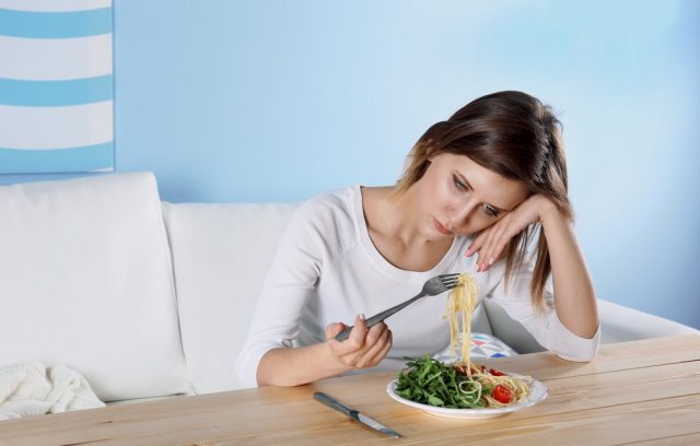 Persistent Depressive Disorder: Young depressed girl with eating disorder at wooden table