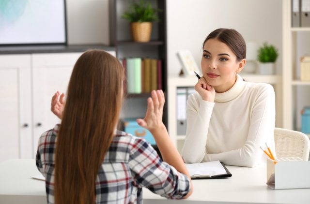 Persistent Depressive Disorder: Young female psychologist working with teenager girl in office