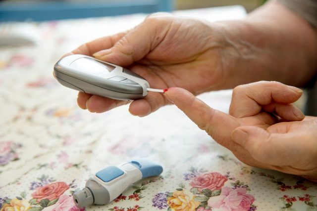 Senior woman is checking her sugar level with glucometer.