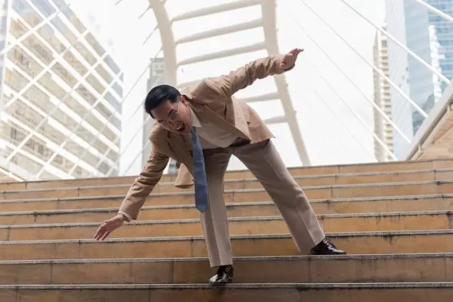 Businessman falling down the steps of staircase