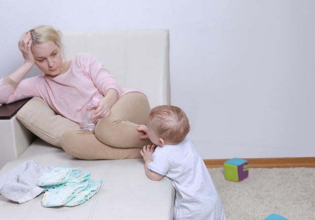Woman sits with her child, postpartum depression