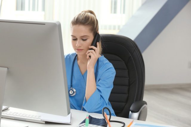 Young medical assistant talking by telephone while working in office